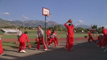 Movie still from “High School Musical” (2006), directed by Kenny Ortega – A group of young men playing a game of basketball; Extreme Wide shot, Low angle