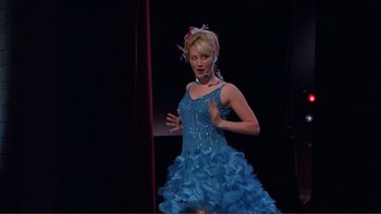 Movie still from “High School Musical” (2006), directed by Kenny Ortega – A woman in a blue dress on a stage in front of a red curtain; Wide shot, Low angle