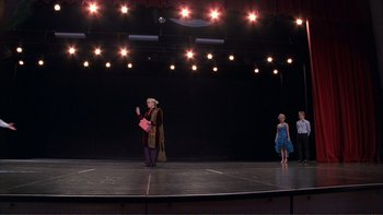 Movie still from “High School Musical” (2006), directed by Kenny Ortega – A couple of people on a stage with lights in the background; Extreme Wide shot, Low angle