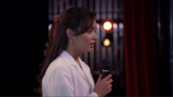 Movie still from “High School Musical” (2006), directed by Kenny Ortega – A woman is holding a microphone in her hand; Close Up shot, Over the shoulder angle