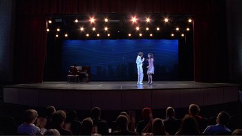 Movie still from “High School Musical” (2006), directed by Kenny Ortega – A couple of people on a stage in front of a crowd; Extreme Wide shot, Low angle
