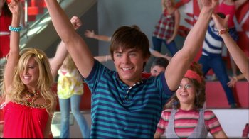 Movie still from “High School Musical 2” (2007), directed by Kenny Ortega – A young man holding his hands up in the air; Medium shot, Low angle