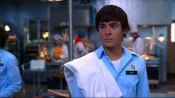 Movie still from “High School Musical 2” (2007), directed by Kenny Ortega – A man in a blue shirt and white shirt holding a white towel; Close Up shot, Over the shoulder angle