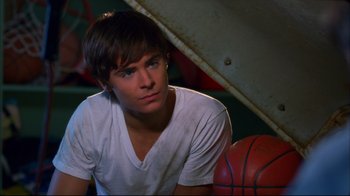 Movie still from “High School Musical 2” (2007), directed by Kenny Ortega – A young man sitting next to a basketball on the ground; Close Up shot, Over the shoulder angle