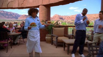 Movie still from “High School Musical 2” (2007), directed by Kenny Ortega – A man holding a tray of food on top of an outdoor patio; Medium shot, Over the shoulder angle
