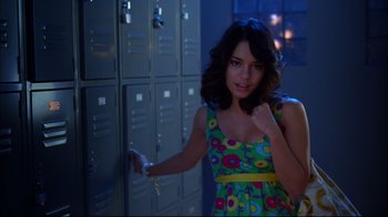 Movie still from “High School Musical 2” (2007), directed by Kenny Ortega – A woman in a colorful dress standing in front of lockers; Medium shot, Over the shoulder angle