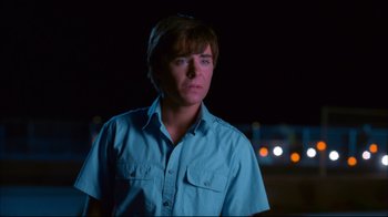 Movie still from “High School Musical 2” (2007), directed by Kenny Ortega – A man in a blue shirt is standing in the dark; Close Up shot, Over the shoulder angle