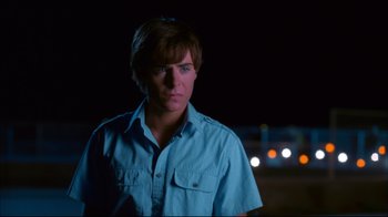 Movie still from “High School Musical 2” (2007), directed by Kenny Ortega – A man in a blue shirt is standing in the dark; Close Up shot, Over the shoulder angle