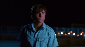 Movie still from “High School Musical 2” (2007), directed by Kenny Ortega – A man in a blue shirt is looking at the camera; Medium shot, Over the shoulder angle