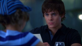 Movie still from “High School Musical 2” (2007), directed by Kenny Ortega – A young man sitting at a table with a glass of wine; Close Up shot, Over the shoulder angle