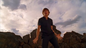 Movie still from “High School Musical 2” (2007), directed by Kenny Ortega – A young man standing in front of a rock wall; Medium shot, Low angle