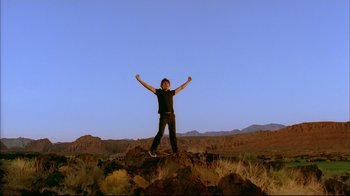 Movie still from “High School Musical 2” (2007), directed by Kenny Ortega – A man standing on top of a hill with his arms in the air; Wide shot, Low angle