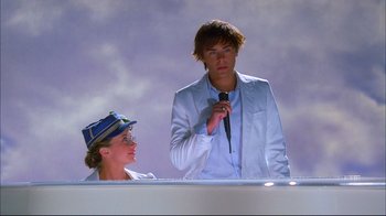 Movie still from “High School Musical 2” (2007), directed by Kenny Ortega – A man and a woman standing next to each other on a boat; Medium shot, Low angle