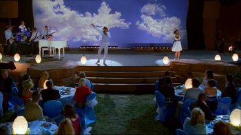 Movie still from “High School Musical 2” (2007), directed by Kenny Ortega – A couple of people on a stage in front of a crowd; Extreme Wide shot, High angle