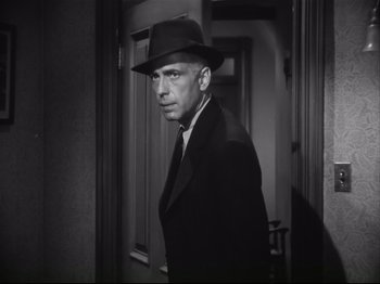 Movie still from “High Sierra” (1940), directed by Raoul Walsh – A black and white photo of a man in a suit and hat; Close Up shot, Low angle