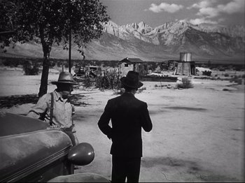 Movie still from “High Sierra” (1940), directed by Raoul Walsh – Two men standing next to each other on a dirt road; Wide shot, Low angle