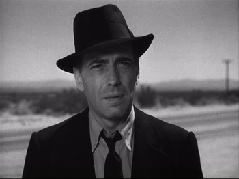 Movie still from “High Sierra” (1940), directed by Raoul Walsh – A black and white photo of a man wearing a suit and a hat; Close Up shot, Low angle