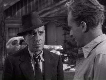 Movie still from “High Sierra” (1940), directed by Raoul Walsh – A man wearing a suit and a hat talking to another man wearing a hat; Close Up shot, Over the shoulder angle