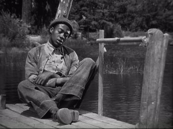 Movie still from “High Sierra” (1940), directed by Raoul Walsh – A black and white photo of a man sitting on a dock; Medium shot, High angle
