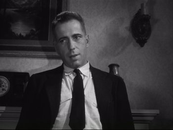 Movie still from “High Sierra” (1940), directed by Raoul Walsh – A black and white photo of a man wearing a suit and tie; Close Up shot, Low angle