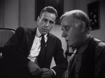 Movie still from “High Sierra” (1940), directed by Raoul Walsh – A man in a suit talks to another man in a suit; Medium shot, Over the shoulder angle