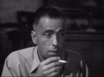 Movie still from “High Sierra” (1940), directed by Raoul Walsh – A black and white photo of a man smoking a cigarette; Close Up shot, Low angle