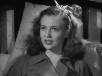 Movie still from “High Sierra” (1940), directed by Raoul Walsh – A young woman in a trench coat is sitting in a bed; Close Up shot, High angle