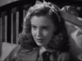 Movie still from “High Sierra” (1940), directed by Raoul Walsh – A young woman with long curly hair wearing a trench coat; Close Up shot, High angle