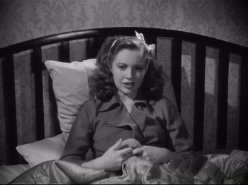 Movie still from “High Sierra” (1940), directed by Raoul Walsh – A woman sitting in a bed with a pillow in front of her face; Medium shot, High angle