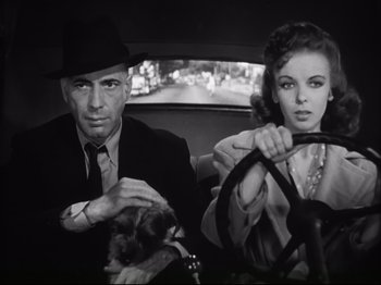 Movie still from “High Sierra” (1940), directed by Raoul Walsh – A man and a woman sitting in a car with a dog; Close Up shot, Low angle
