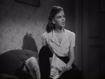 Movie still from “High Sierra” (1940), directed by Raoul Walsh – A woman sitting on a couch holding a newspaper; Medium shot, Low angle