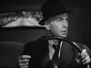 Movie still from “High Sierra” (1940), directed by Raoul Walsh – A black and white photo of a man driving a car; Close Up shot, Low angle