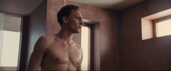 Movie still from “High-Rise” (2015), directed by Ben Wheatley – A shirtless man looking into a bathroom mirror; Medium shot, Low angle