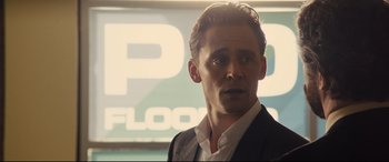 Movie still from “High-Rise” (2015), directed by Ben Wheatley – A person wearing a suit and tie; Close Up shot, Over the shoulder angle