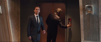 Movie still from “High-Rise” (2015), directed by Ben Wheatley – A man in a suit and tie next to another man in a suit and tie; Medium shot, Low angle