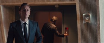 Movie still from “High-Rise” (2015), directed by Ben Wheatley – Two men in suits and hats in an elevator; Medium shot, Over the shoulder angle