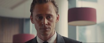 Movie still from “High-Rise” (2015), directed by Ben Wheatley – A person wearing a suit and tie; Close Up shot, Over the shoulder angle