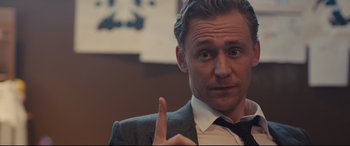 Movie still from “High-Rise” (2015), directed by Ben Wheatley – A person wearing a suit and tie; Close Up shot, Over the shoulder angle