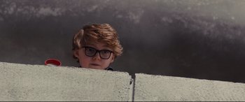 Movie still from “High-Rise” (2015), directed by Ben Wheatley – A boy with glasses is looking over a wall; Medium shot, Low angle