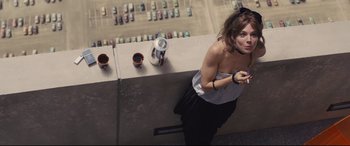 Movie still from “High-Rise” (2015), directed by Ben Wheatley – A woman standing on a ledge with a cup of coffee; Medium shot, Overhead angle