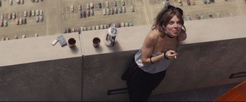 Movie still from “High-Rise” (2015), directed by Ben Wheatley – A woman standing next to a wall with a cup of coffee; Medium shot, Overhead angle