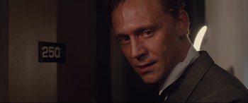Movie still from “High-Rise” (2015), directed by Ben Wheatley – A person wearing a suit and tie; Close Up shot, Over the shoulder angle