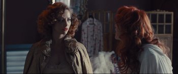 Movie still from “High-Rise” (2015), directed by Ben Wheatley – A woman with red curly hair standing next to another woman; Medium shot, Over the shoulder angle