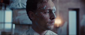 Movie still from “High-Rise” (2015), directed by Ben Wheatley – A person with paint all over his face; Close Up shot, Over the shoulder angle