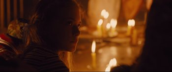 Movie still from “High-Rise” (2015), directed by Ben Wheatley – A girl is sitting in front of a candle lit fireplace; Close Up shot, Over the shoulder angle