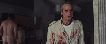 Movie still from “High-Rise” (2015), directed by Ben Wheatley – A man in a white jacket with blood all over it; Close Up shot, Low angle