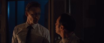 Movie still from “High-Rise” (2015), directed by Ben Wheatley – A man looking at himself in the mirror in the dark; Medium shot, Over the shoulder angle