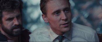 Movie still from “High-Rise” (2015), directed by Ben Wheatley – A person wearing a suit and tie; Close Up shot, Over the shoulder angle