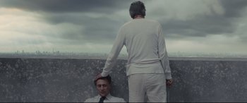 Movie still from “High-Rise” (2015), directed by Ben Wheatley – A man standing next to another man on a ledge; Medium shot, Over the shoulder angle