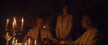 Movie still from “High-Rise” (2015), directed by Ben Wheatley – A man and a woman sitting at a table with a glass of red wine; Medium shot, Over the shoulder angle